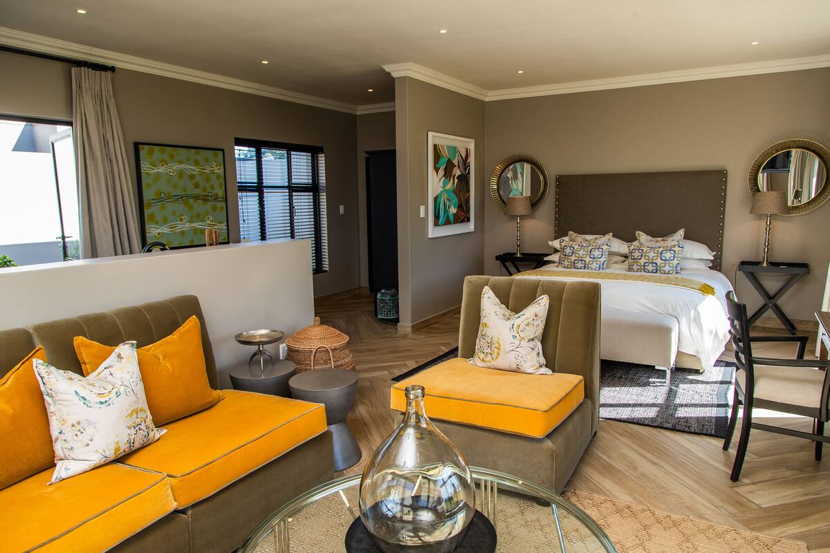 Una habitación de hotel con cama, sofá, mesa de centro y mesa de comedor.