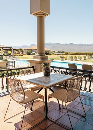 An outdoor patio with a table and chairs, a pool, and mountains in the background. - Sante Wellness Retreat & Spa (Paarl)