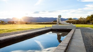 A sculpture of a reclining figure on a pedestal by a reflective pool with a mountain backdrop. - Sante Wellness Retreat & Spa (Paarl)