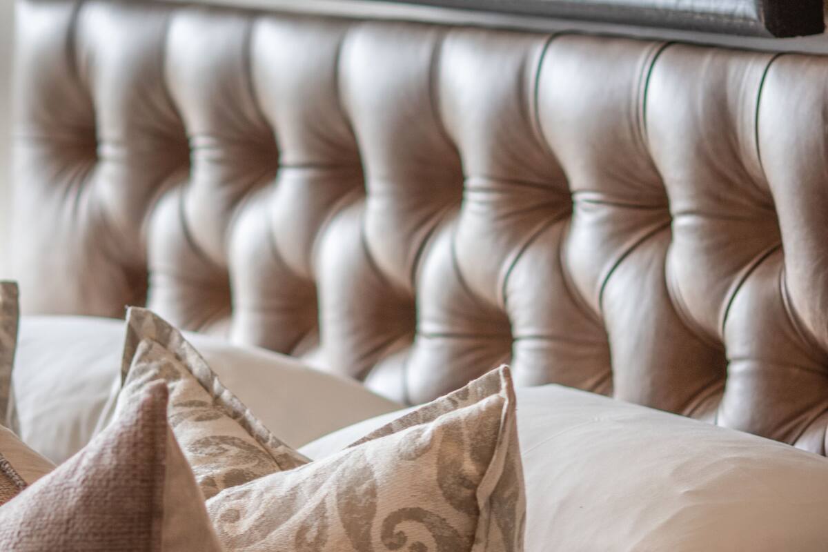 Cabecera tapizada con almohadones decorativos y un cuadro enmarcado arriba.