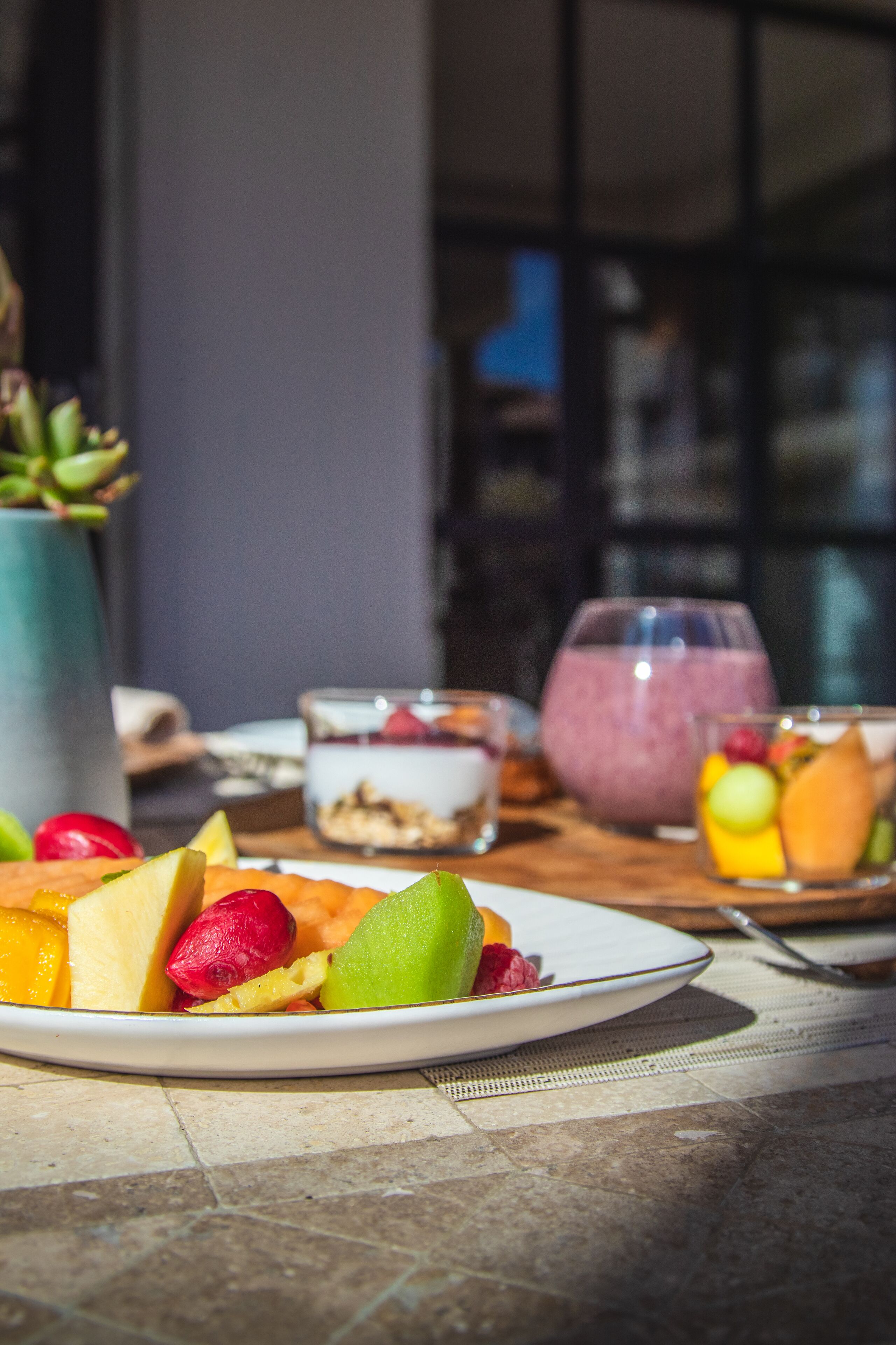 Una mesa con una ensalada de frutas y un vaso de batido.