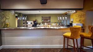 Un espace bar comprenant un comptoir, des tabourets de bar et une variété de bouteilles et de verres.