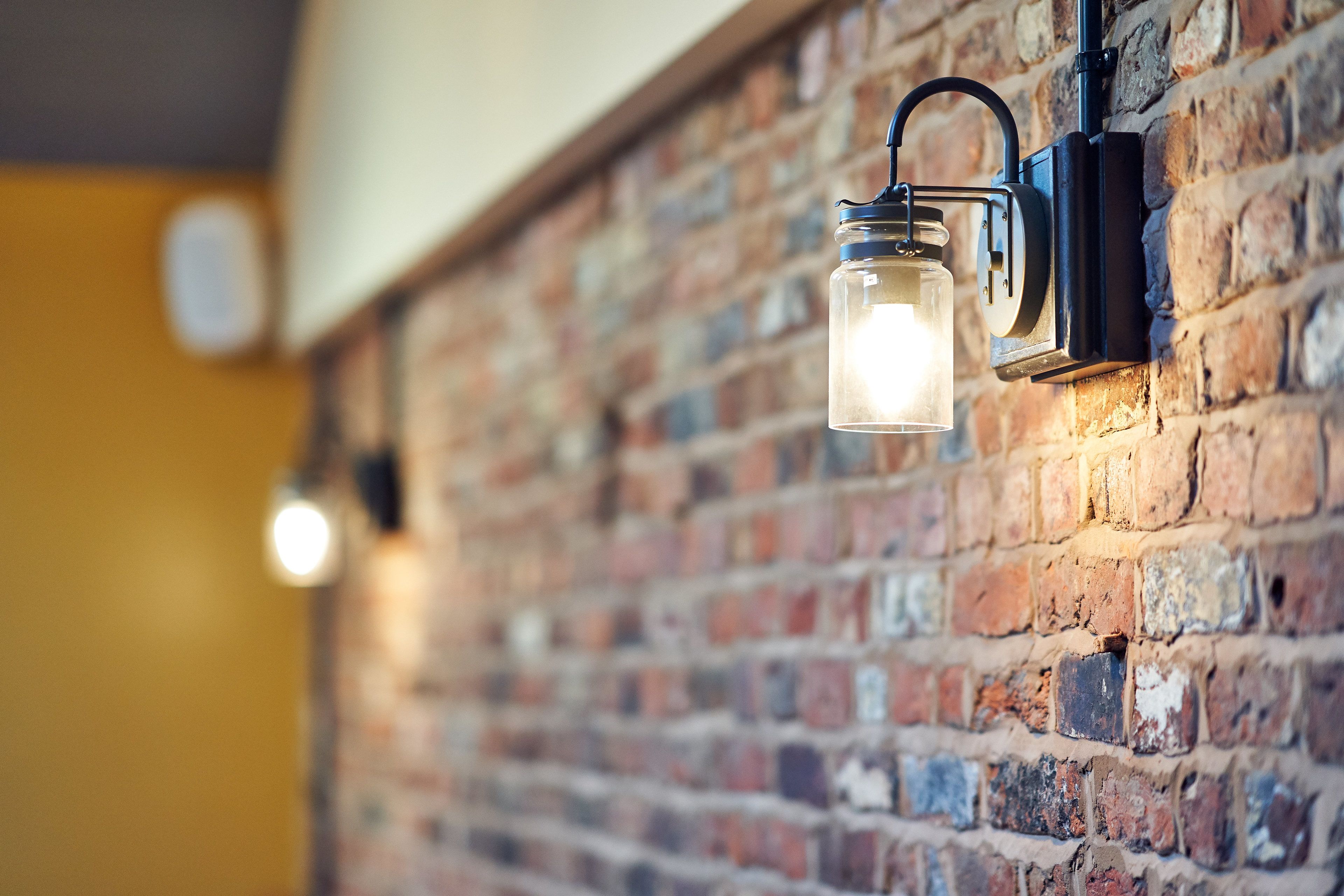 A brick wall with a hanging light fixture.