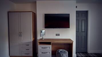 Una camera da letto con un letto, un armadio, una scrivania e una porta, oltre a una televisione a schermo piatto.