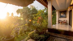 A well-maintained garden with potted plants and a bench, leading to a clean and modern interior with a framed artwork on the wall. - Ubud Wins Bungalow (Ubud)