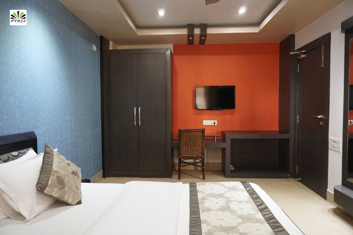 A hotel room with a bed, a wardrobe, a desk, and a television.