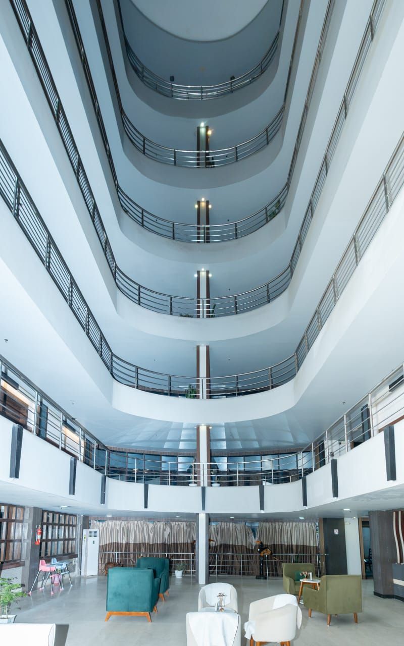 A multi-level atrium with a central staircase, seating areas, and a view of the lower floors.