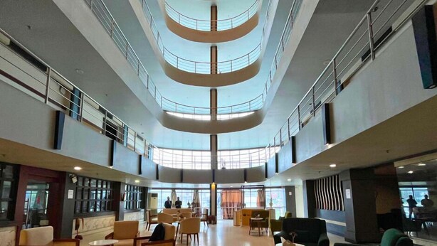 A spacious lobby with multiple seating areas, a central open space, and a high ceiling with a circular design.