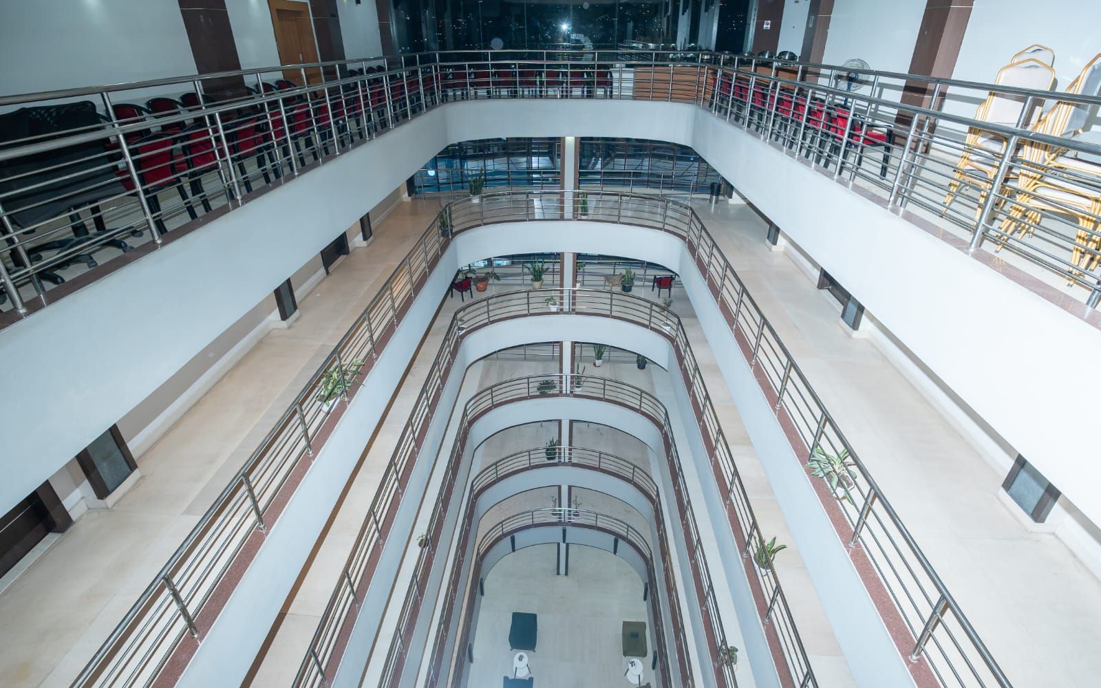 A multi-level atrium with a central staircase, railings, and seating areas.