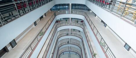 A multi-level atrium with a central staircase, railings, and seating areas.