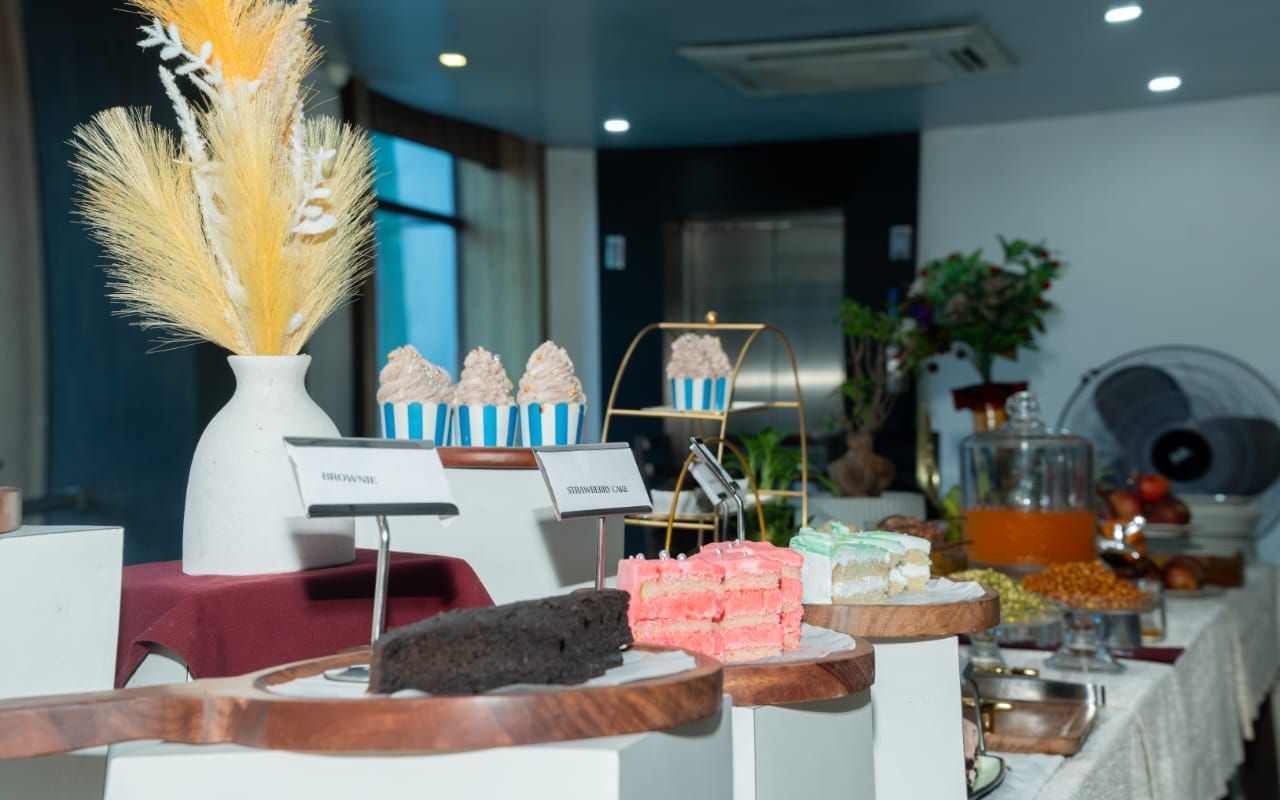 A buffet with various desserts and a sign indicating 'Brownie' and 'Strawberry Cake'.
