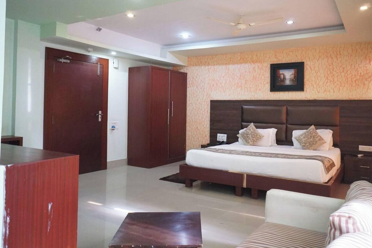 A hotel room with a large bed, a wardrobe, a desk, and a sofa.