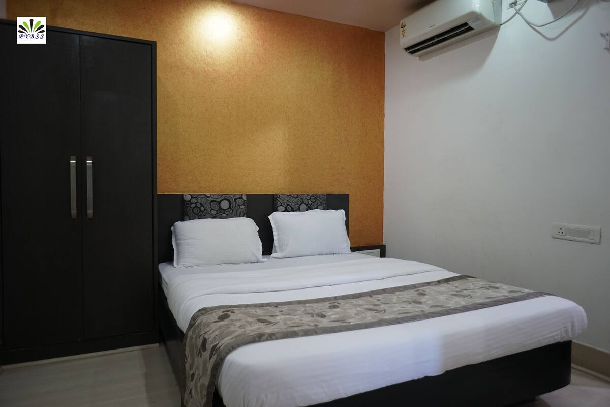 A bedroom with a bed, a wardrobe, and an air conditioning unit.