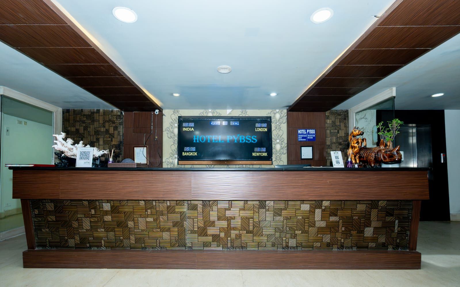 Un mostrador de recepción de hotel con una pantalla digital que muestra el nombre y las ubicaciones del hotel.