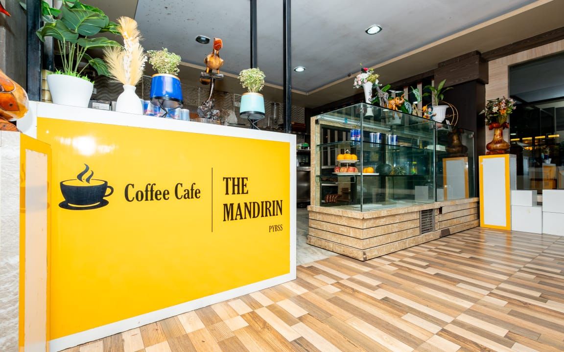 L’intérieur d’un café, avec un comptoir jaune, un plancher en bois, ainsi que diverses plantes et décorations.
