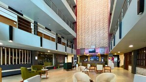A spacious lobby with multiple seating areas, a reception desk, and a large wall-mounted TV.