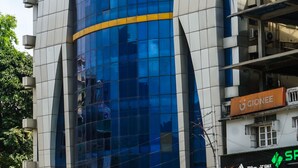 A hotel with a modern design, featuring a prominent glass facade and a sign for 'Hotel PEBSS'.