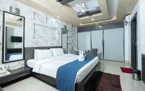 A modern hotel room with a large bed, a bedside table, a mirror, a TV, and a wardrobe. - Hotel Pybss (Papumpare)