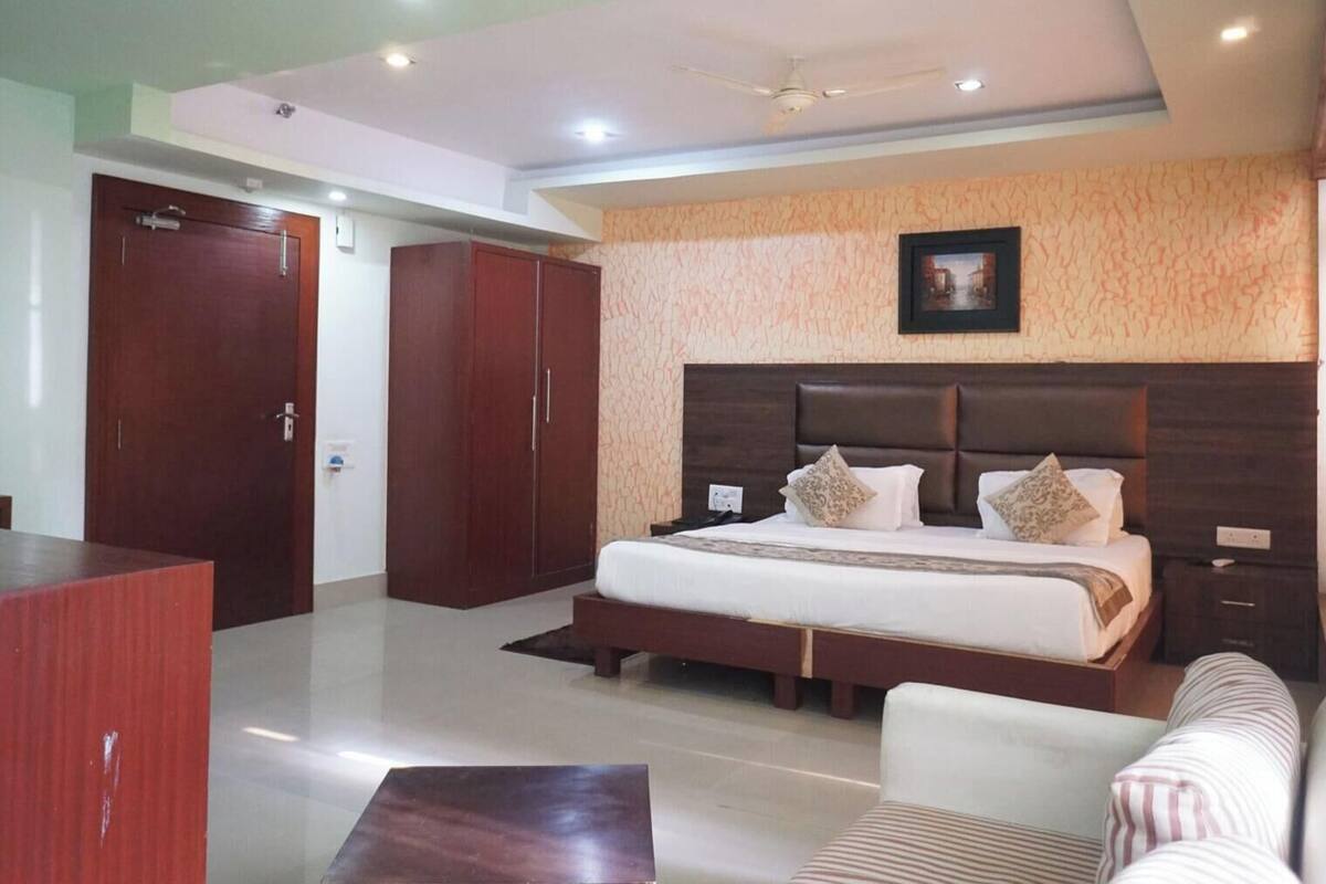 A hotel room with a large bed, a wardrobe, a desk, and a sofa.
