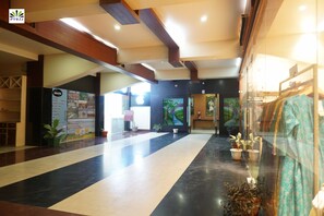 A spacious lobby with a black and white striped floor, wooden beams on the ceiling, and potted plants. - Hotel Pybss (Papumpare)