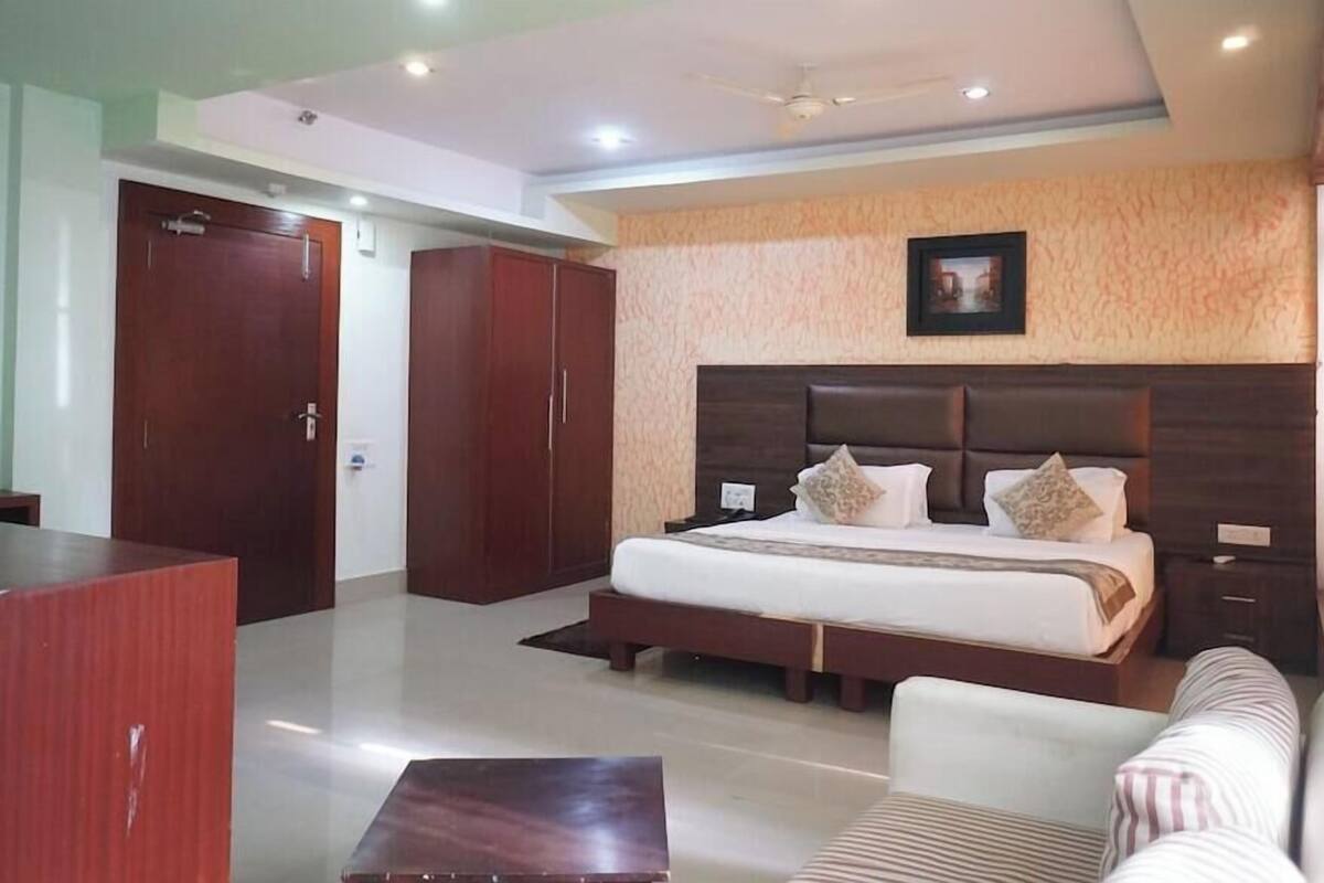 A hotel room with a bed, a desk, a chair, and a wardrobe.
