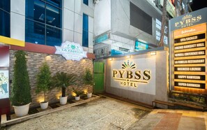 The exterior of the PyBSS Hotel with a sign for La Familia Restaurant and a list of amenities including a spa, conference hall, and business lounge. - Hotel Pybss (Papumpare)