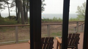 En træterrasse med to Adirondack-stole vendt mod et havudsigt.