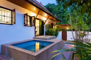 A pool area with a rectangular pool, a wooden deck, and a white wall with a window and door. - Blissful Jacuzzi Living at Villa Nikkie2 (Rawai)