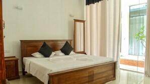 Una cama bien hecha con cabecera de madera, sábanas blancas y dos almohadas negras.