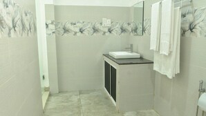 Un baño con lavamanos, espejo y toallero.