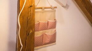 A rustic wooden beam with a white lamp hanging from it, a white power strip, and a white wall with a white curtain with pink polka dots. - Nomado Hostel (Varna)
