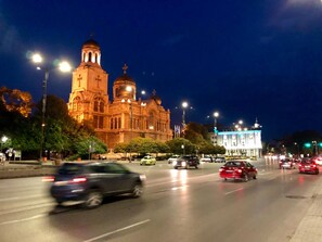 A large, ornate building with multiple domes and a prominent tower, likely a cathedral or church, with a busy street in front. - Nomado Hostel (Varna)