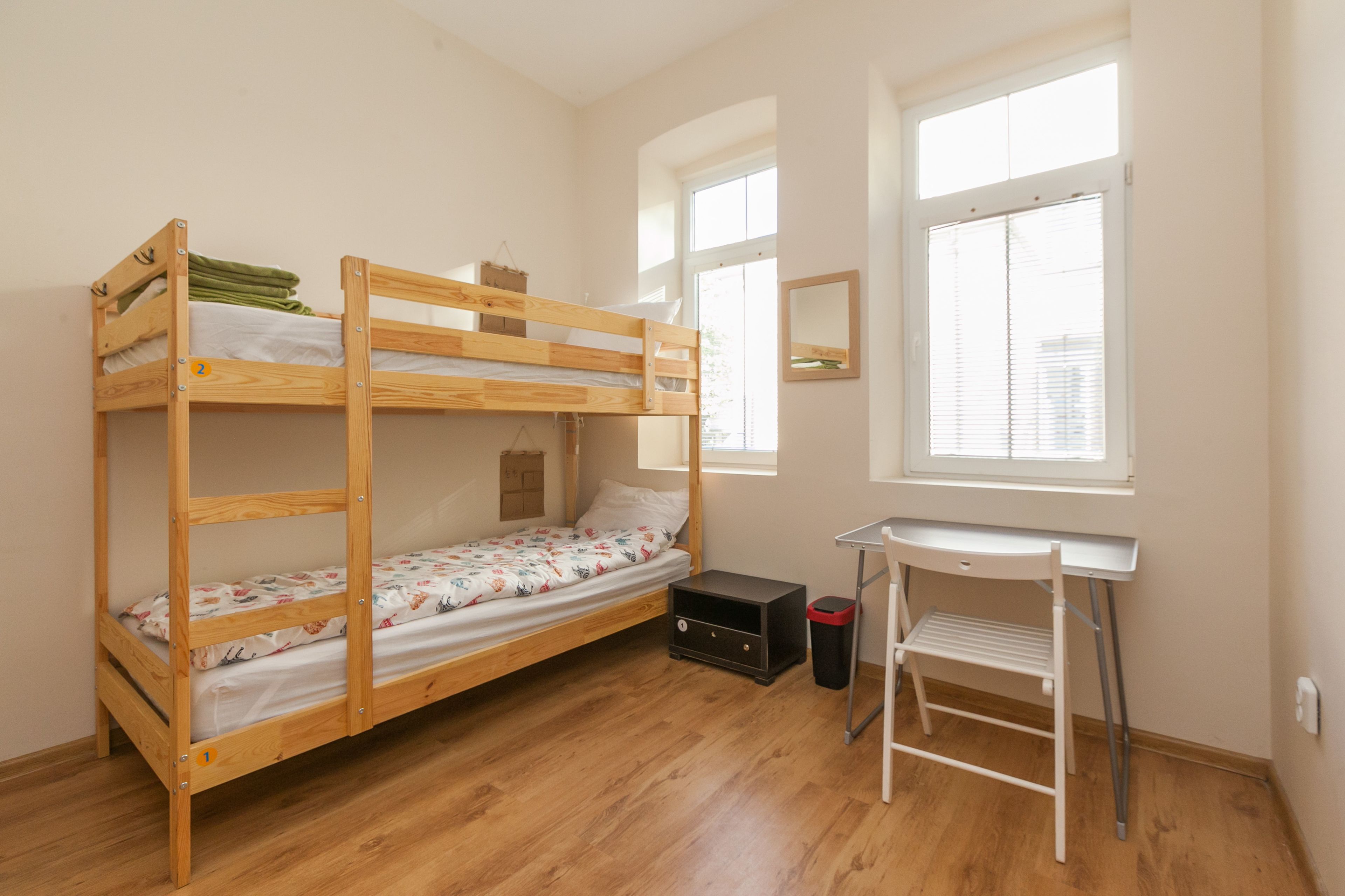 A bunk bed room with a desk and a window.