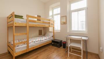 A bunk bed room with a desk and a window.