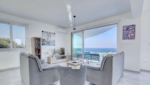 Sala de estar moderna com uma grande porta de vidro deslizante que dá para uma varanda com vista para o mar.