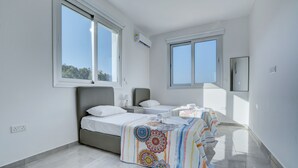 Quarto moderno com duas camas, janelas amplas e vista para o céu.