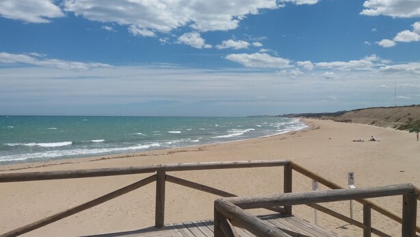 Une plage avec une promenade en bois qui mène au bord de l’eau.
