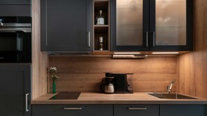 Une cuisine moderne avec des meubles de couleur sombre, un plan de travail en bois, une machine à café et un évier.
