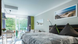 Une chambre moderne avec un grand lit, un balcon avec une table et des chaises, et un tableau accroché au mur.