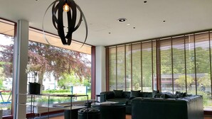 Un salon moderne avec un canapé d’angle, des poufs et un luminaire suspendu.