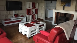 Een woonkamer met rode leren banken, witte opbergmeubels, een open haard en een wandtelevisie.
