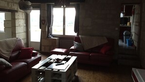 Een woonkamer met een rode bank, een witte salontafel en een raam met gordijnen.