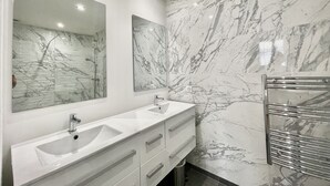 Une salle de bain avec deux lavabos, un grand miroir et un porte-serviettes.