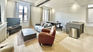 Un salon moderne comprenant un canapé, une table basse, un téléviseur et un coin repas avec une table et des chaises.