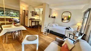 Et hotelværelse med en seng, et siddeområde med et bord og stole, et skrivebord og et stort vindue.