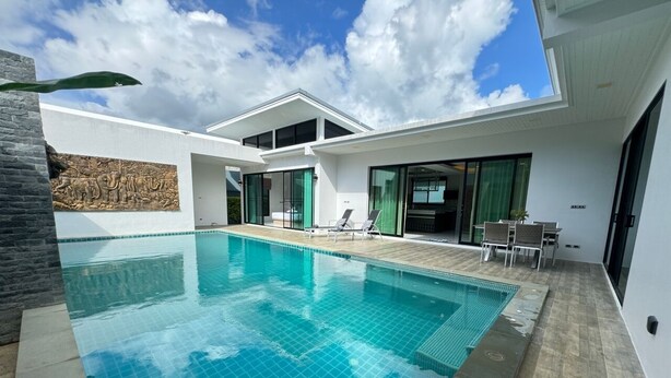 Een modern huis met een zwembad, een terras met stoelen en uitzicht op de lucht.