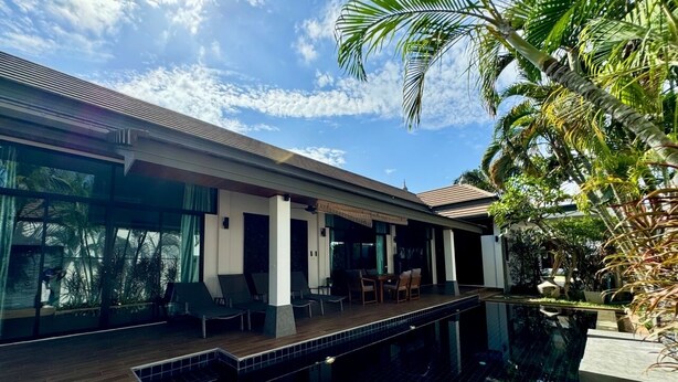 Een modern huis met een zwembad, grote ramen en een terras.