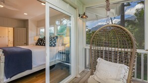 Een slaapkamer met een bed, een stoel en uitzicht op een berg door een groot raam.