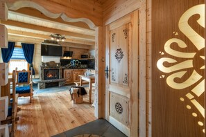 Un interior de madera con chimenea de piedra, comedor y cocina con microondas.