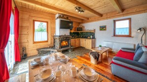 A cozy wooden cabin with a stone fireplace, wooden dining table set, and a comfortable sofa. - Domki Ze Hej z kominkiem lub sauną (Zakopane)